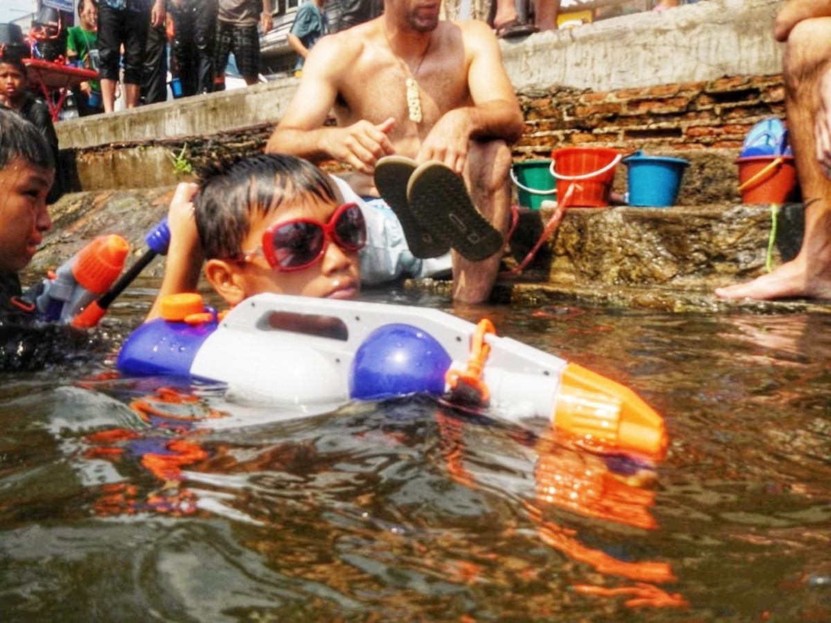 A young boy in goggles lurks during a water fight.