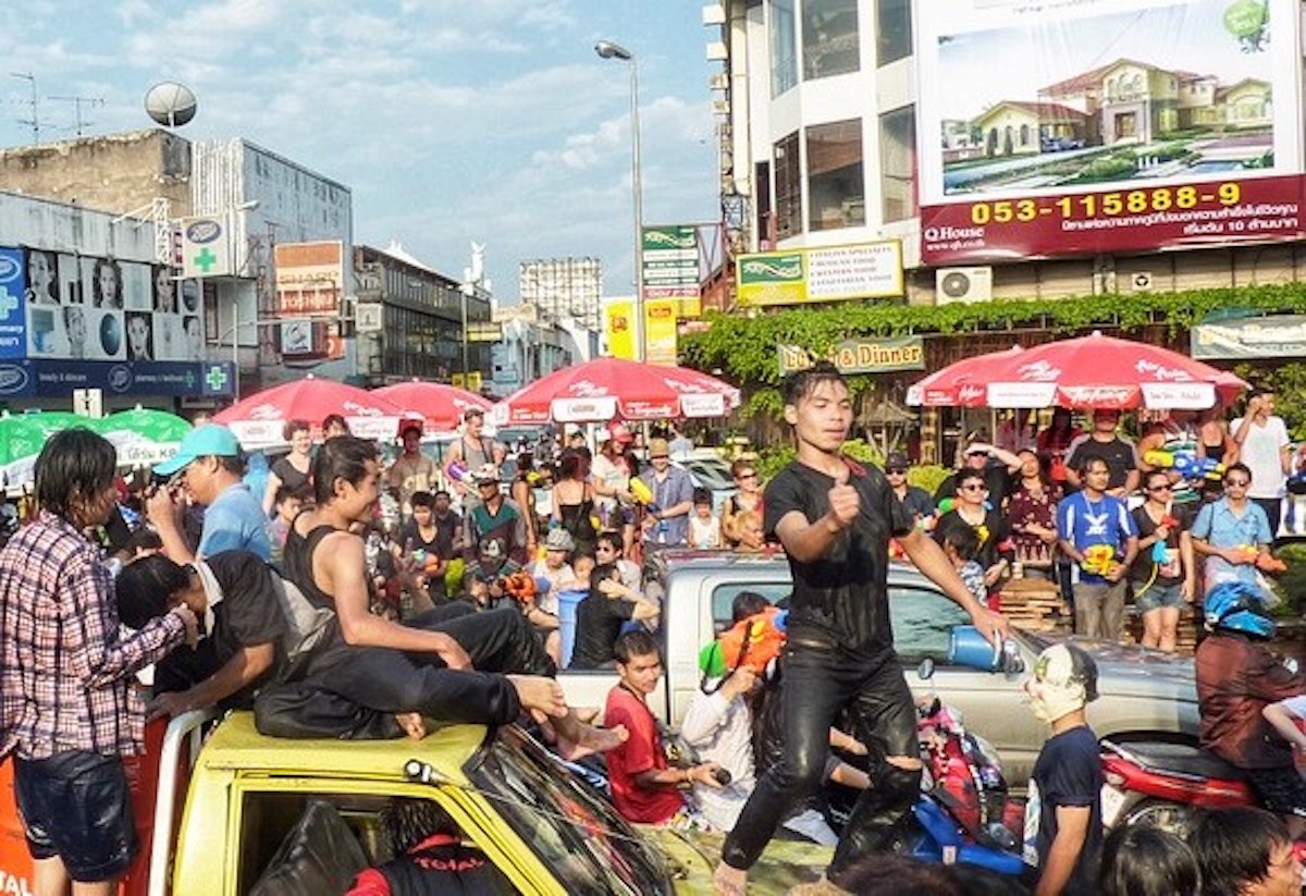 A young boy dances on a car in a packed crowd.