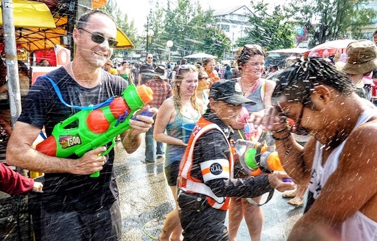 A policewoman laughs as people have a water fight.