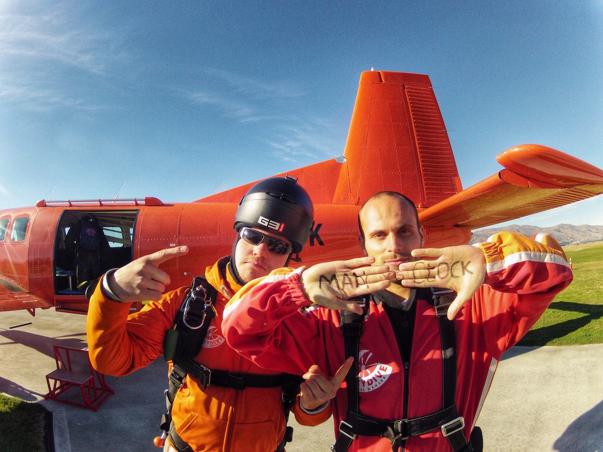 2 men standing outside of a skydiving plane.