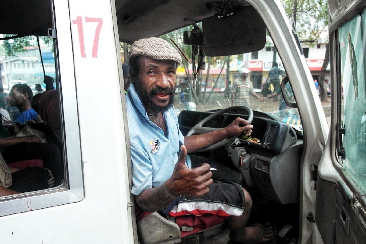 A man driving a bus in Port Moresby, Papua New Guinea 