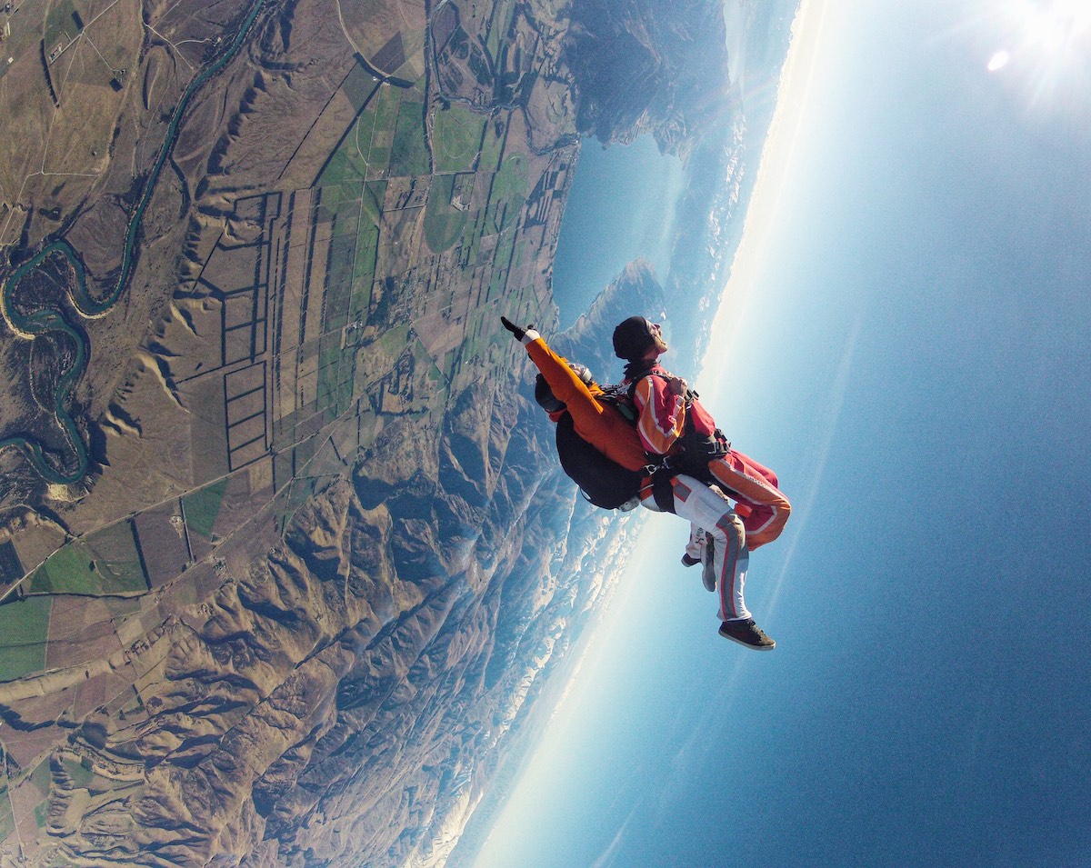 2 men are upside down in a tandem skydive jump. 
