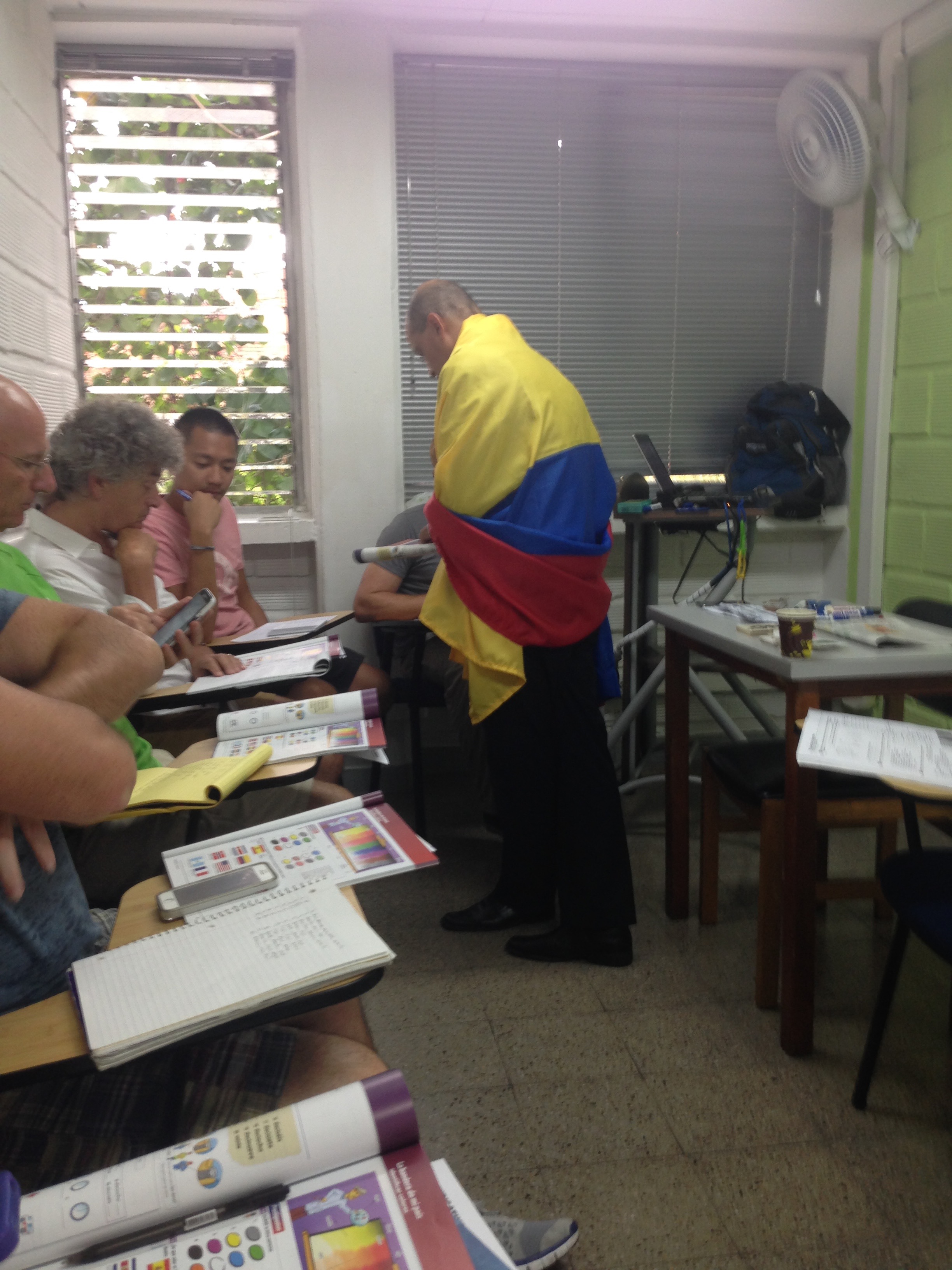 Crazy Colombian teacher draped in Colombian flag while locals study Spanish in Medellin