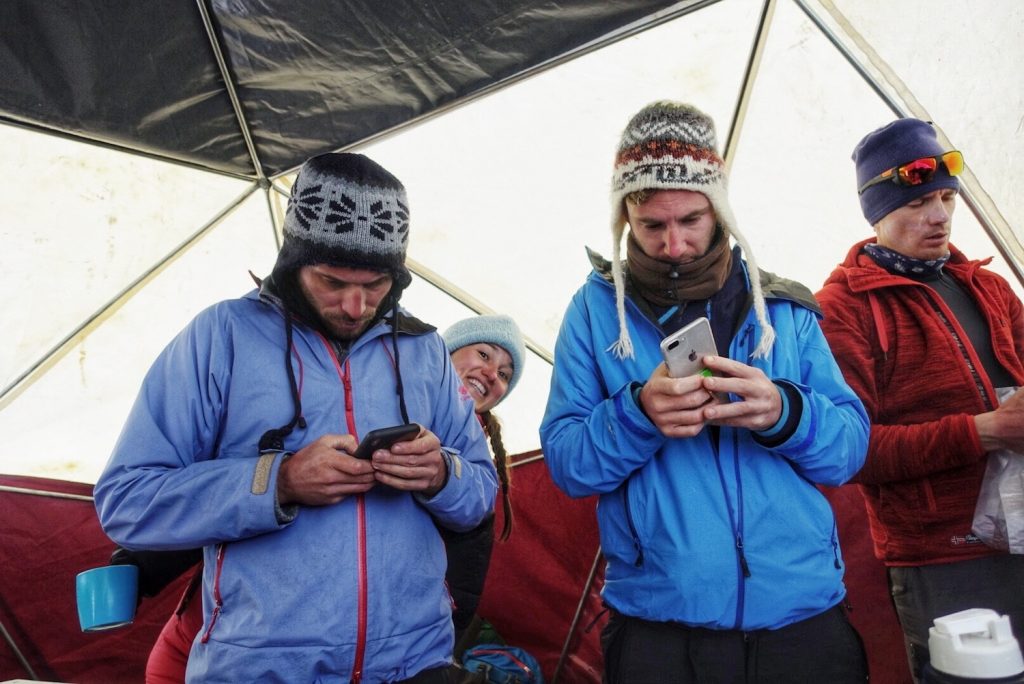 An anxious group of mountain climbers checking the weather forecast on their mobile phones on Aconcagua