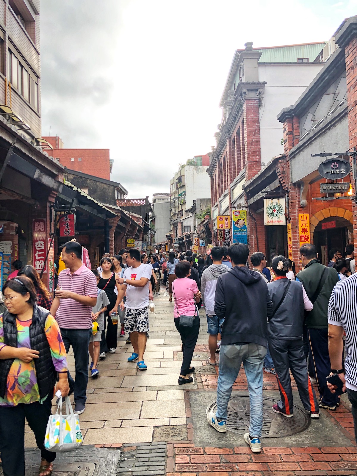 A busy, tight street with people walking down both sides of it