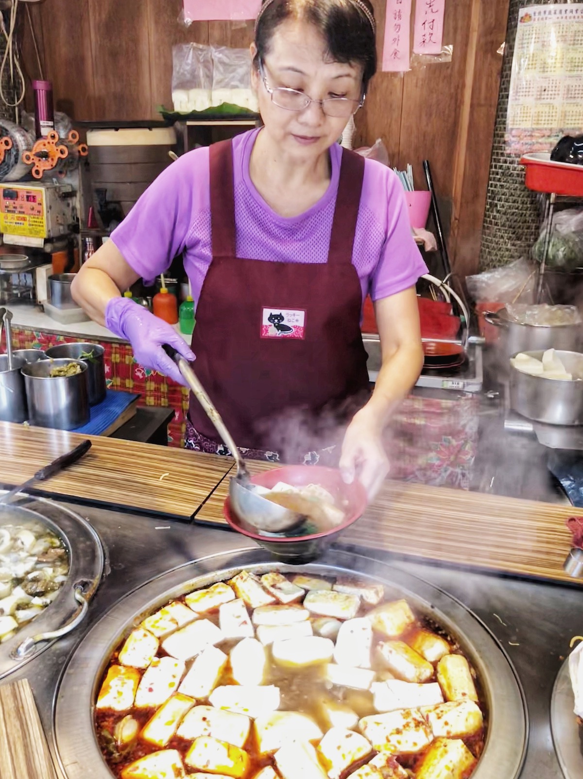 A lady street seller dishes out a huge pot of tofu in Taipei, Taiwan