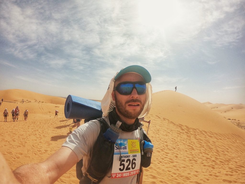 man running through desert with sand dunes