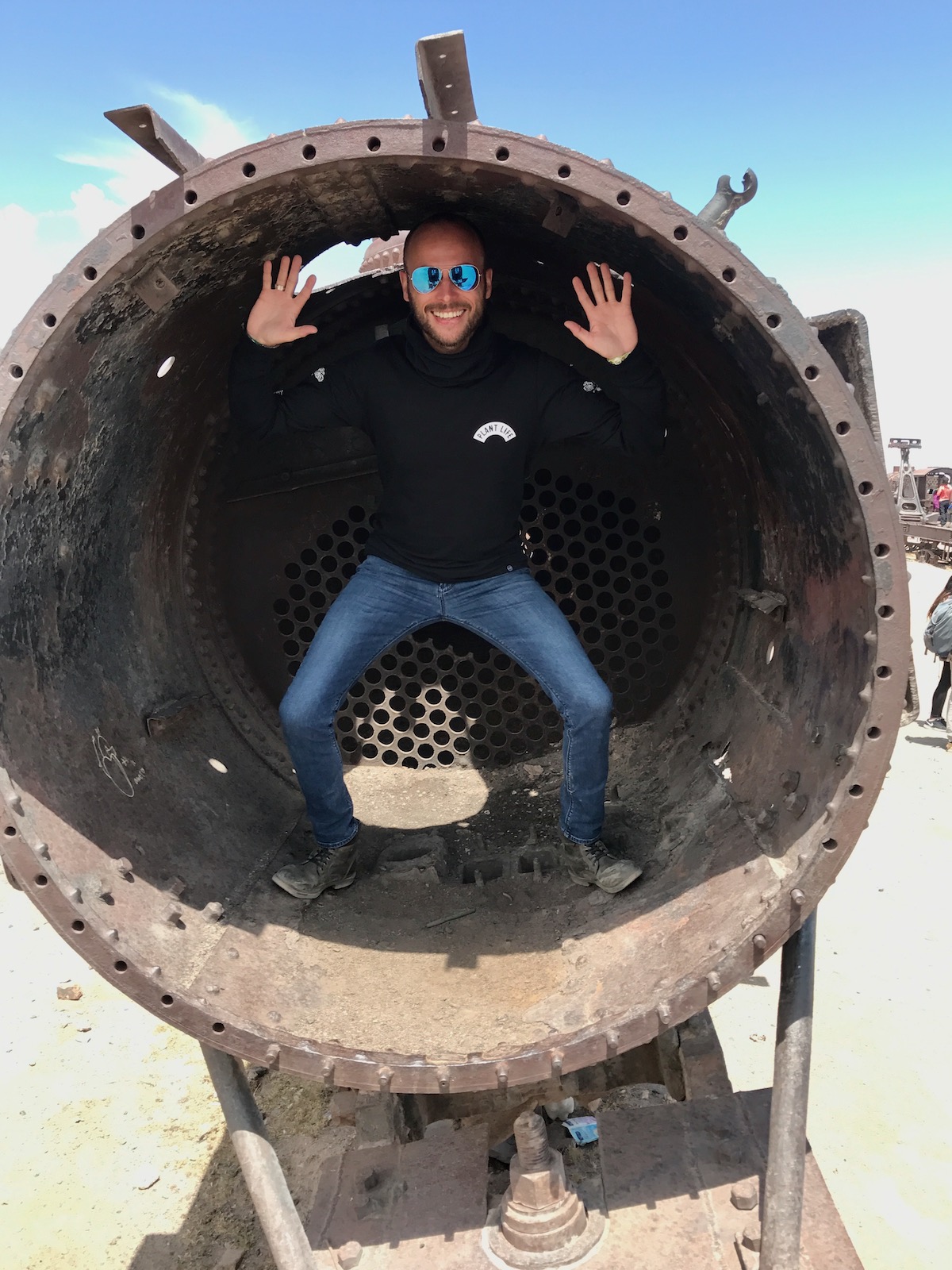 A male tourist poses inside an old train while visiting Salar de Uyuni in Bolivia.