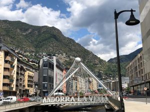 Signpost of Andorra la vella with a large green mountainous hill behind it