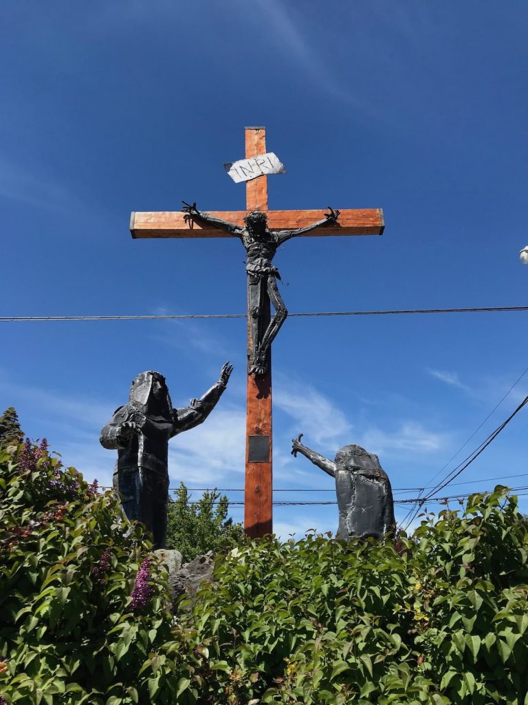 Christian statue of a cruxific with Jesus and two other figures with the backdrop of a blue sky in Argentina, Patagonia