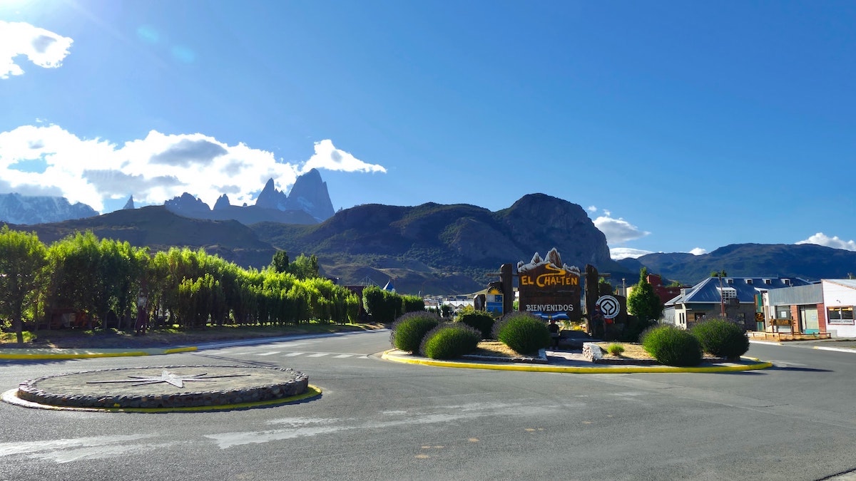 Green trees near a mountain with El Chalten sign on a roundabout in Argentina