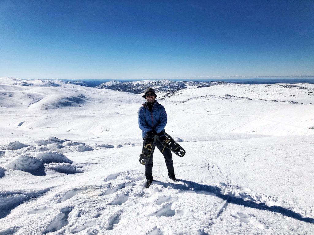 Man holding ski shoes on top of Mount Kosciuszko, Australia