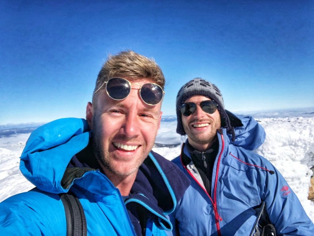 Two men smile after reaching the top of Australia's tallest mountain