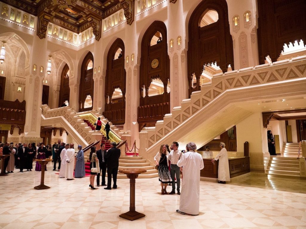People in traditional Omani dress stand in the Royal Opera House in Muscat