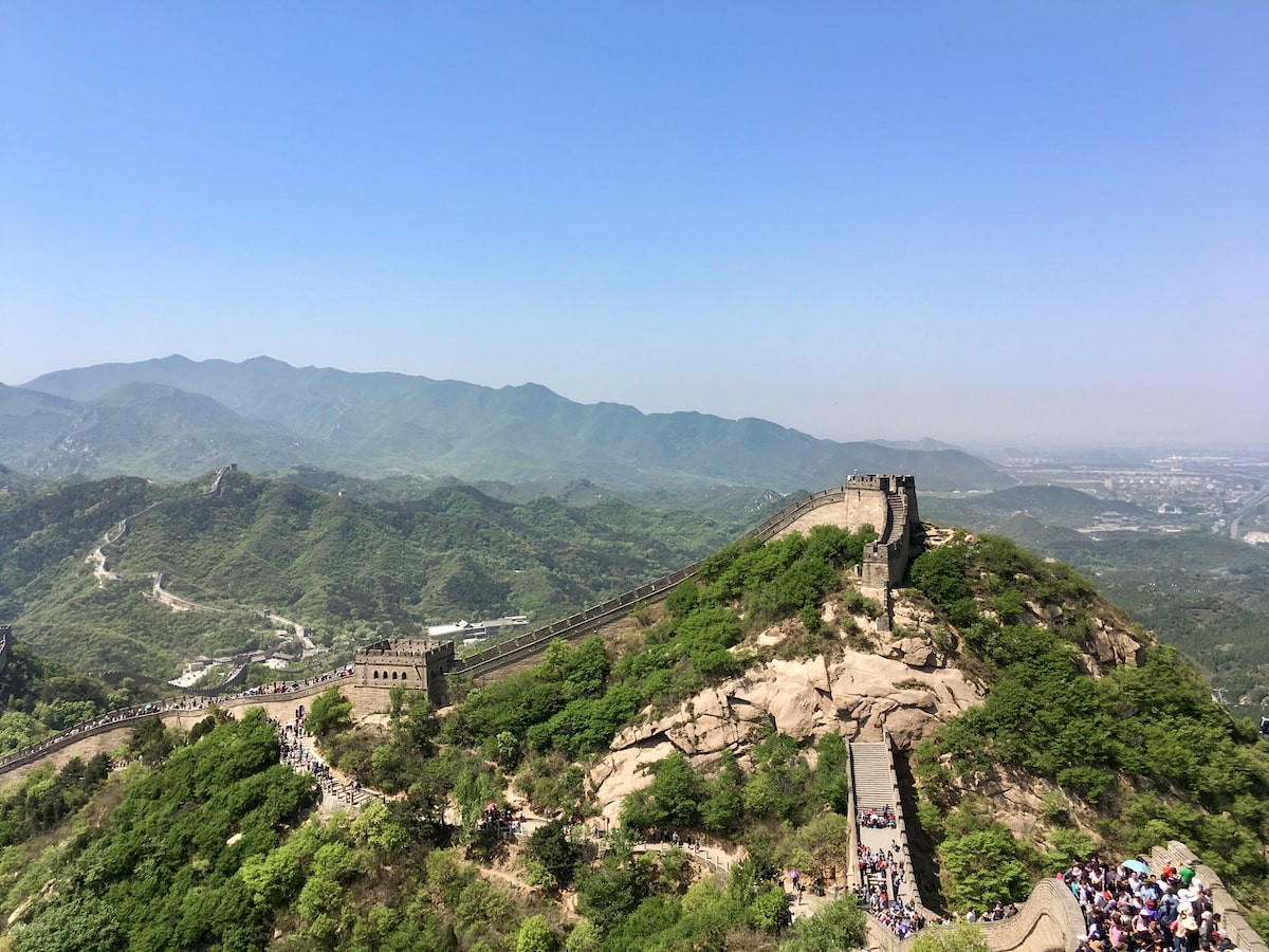 A busy flock of tourists on the Great Wall of China on a sunny day.