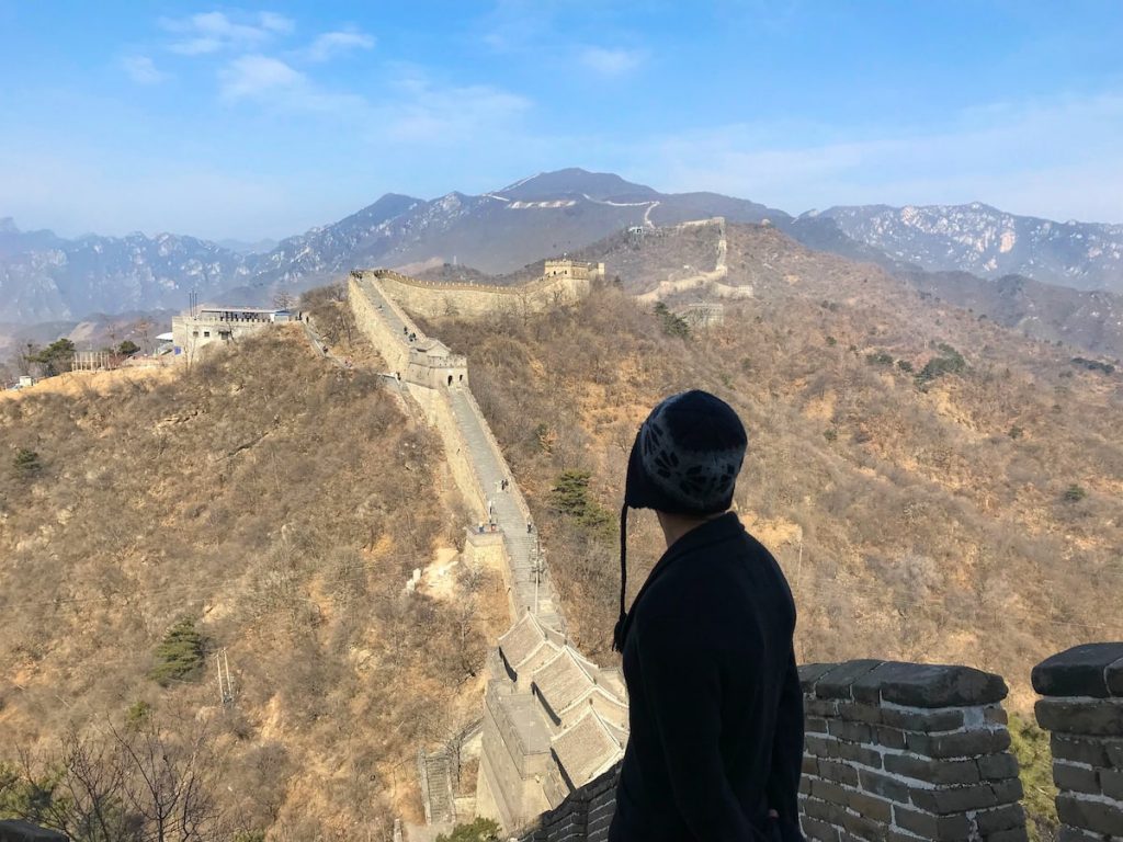 A tourist looks out into a landscape of the Great Wall of China.