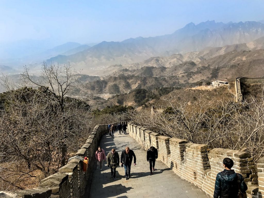 Tourists walk over a bridge with a mountainous backdrop in Beijing, China. 