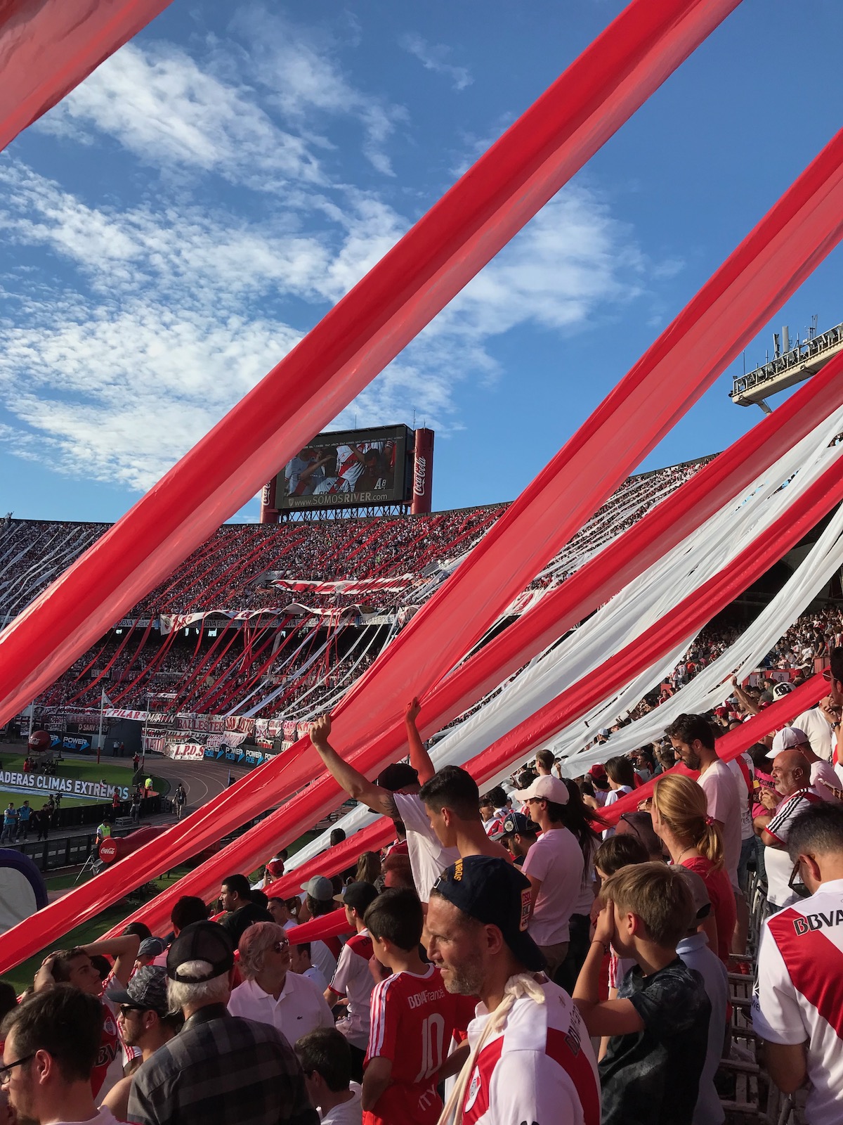Red and white flares dangle below football fans in a packed stadium in Buenos Aires