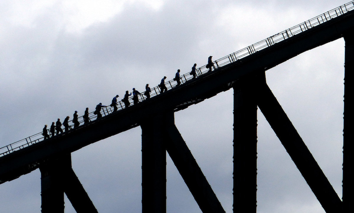 A tour group walk up a steep incline in the sky in Sydney, Australia. 