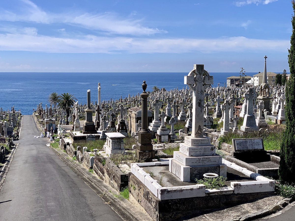 A large cemetery overlooks the sea on a bright blue day. 