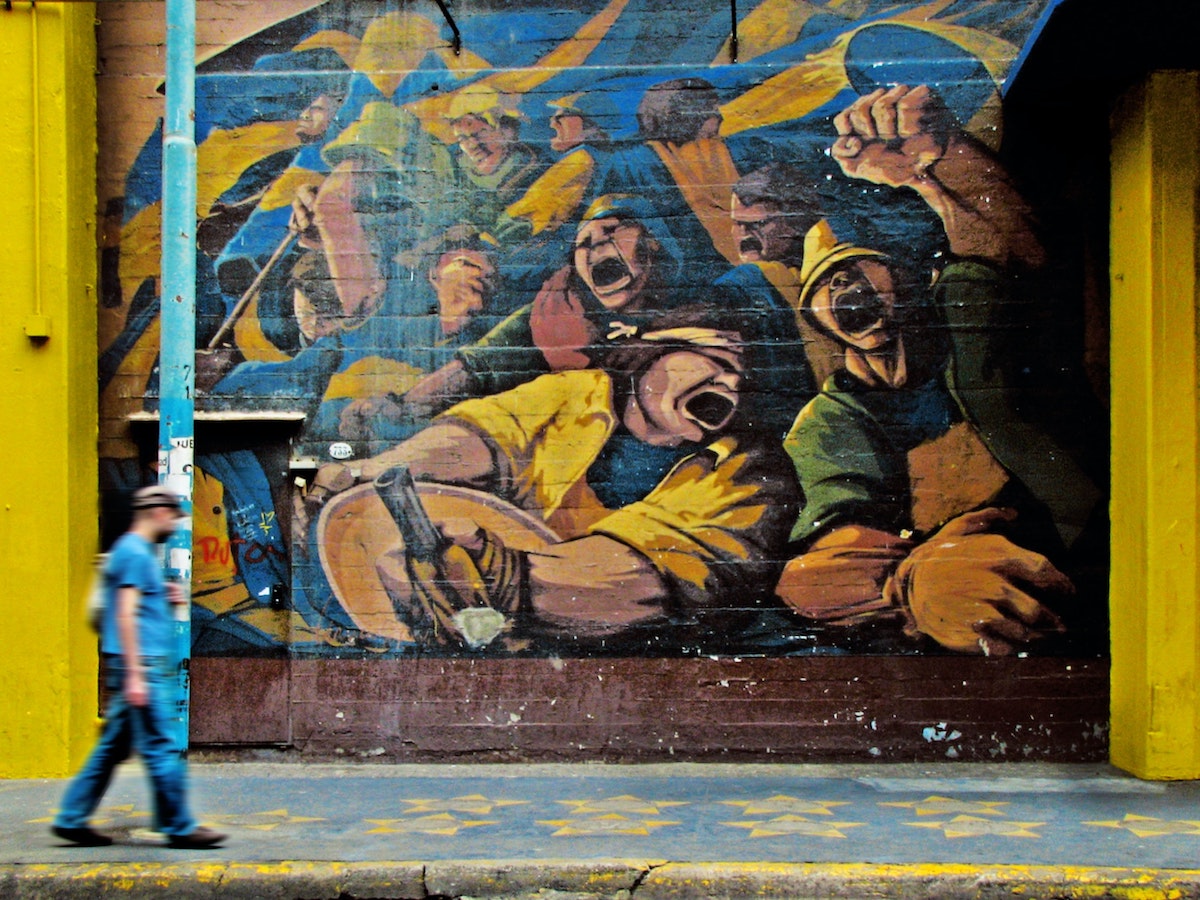 Man walks past graffiti depicting Boca Juniors supporters in Buenos Aires, Argentina