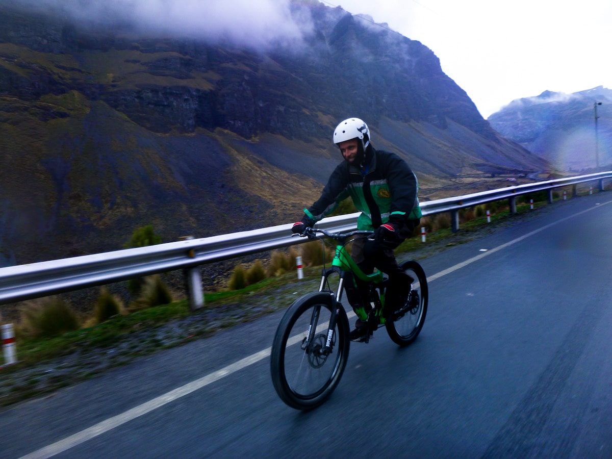 Tourist smiles in green close while cycling down the Death Road in Bolivia.