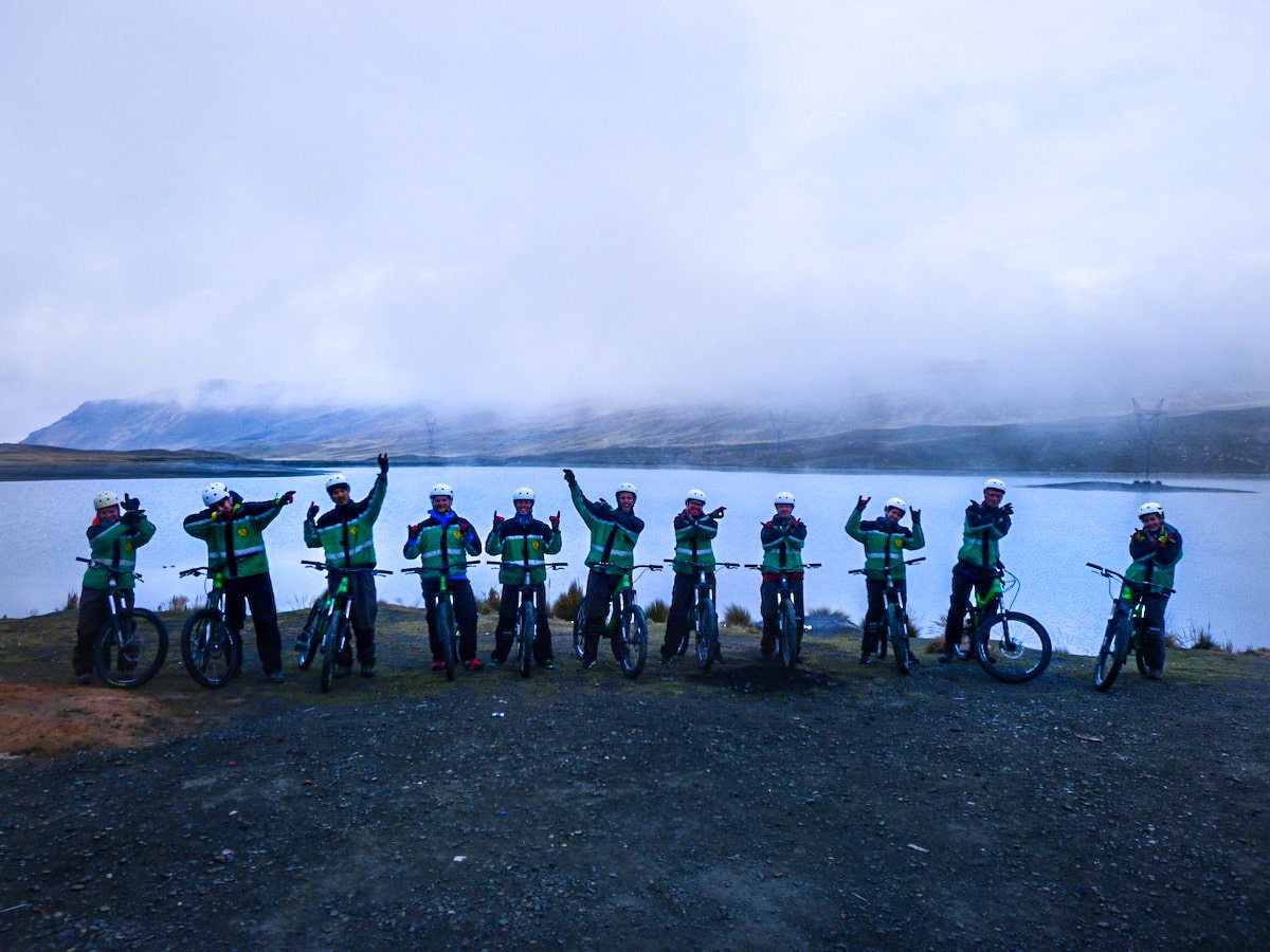 A team of cyclists pose with arms in the air at the start of Bolivia's Death Road.
