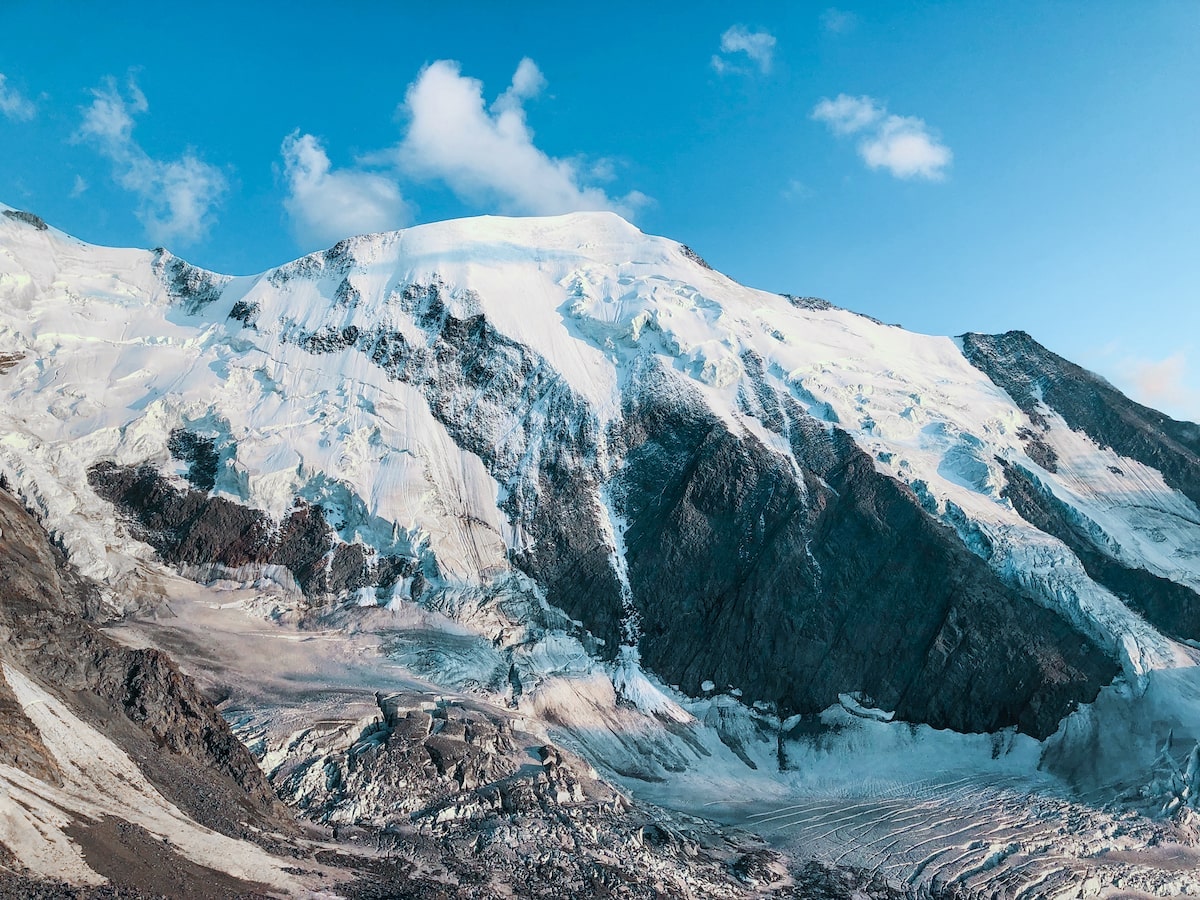 A snow-capped black mountain on a bright blue-skyed day.