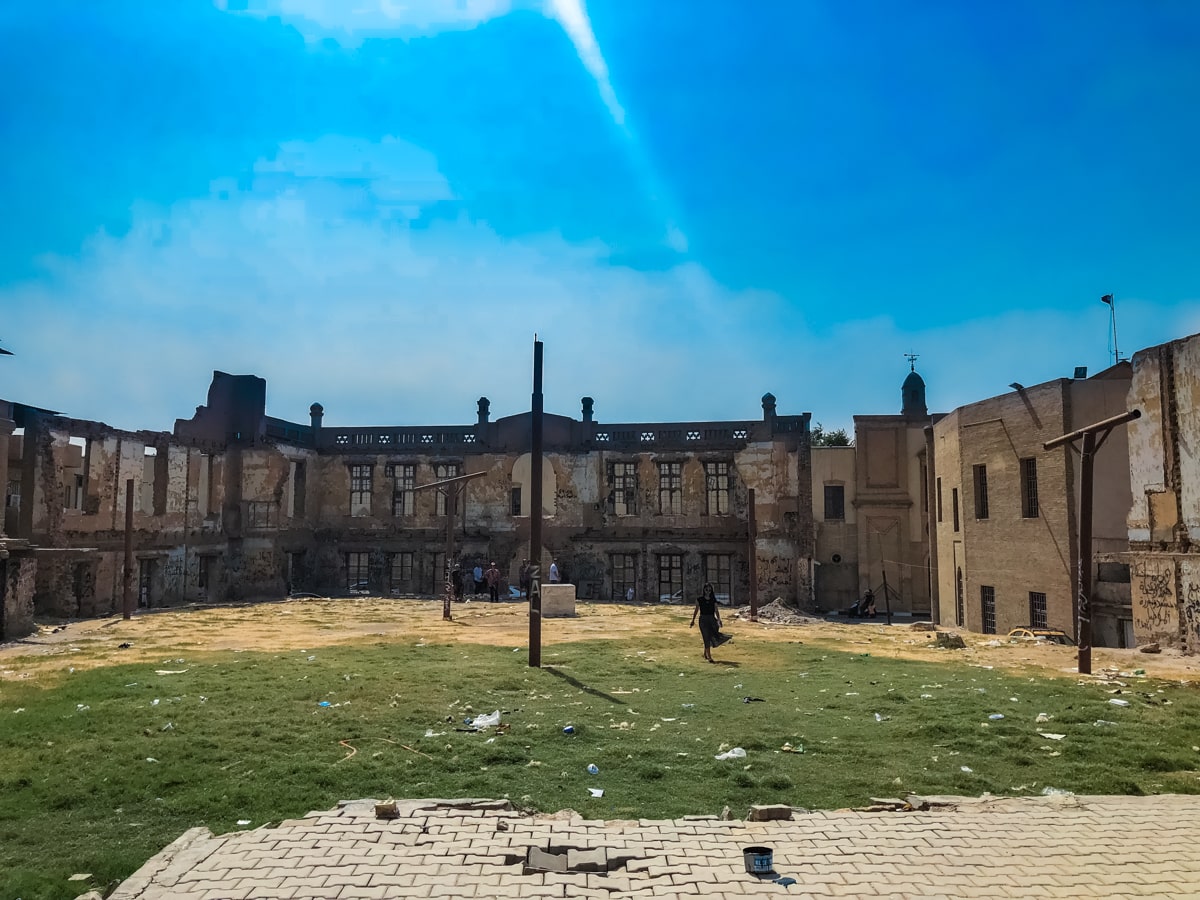 A woman in a black dress walks outside the ruins of the former British Club in Baghdad, Iraq