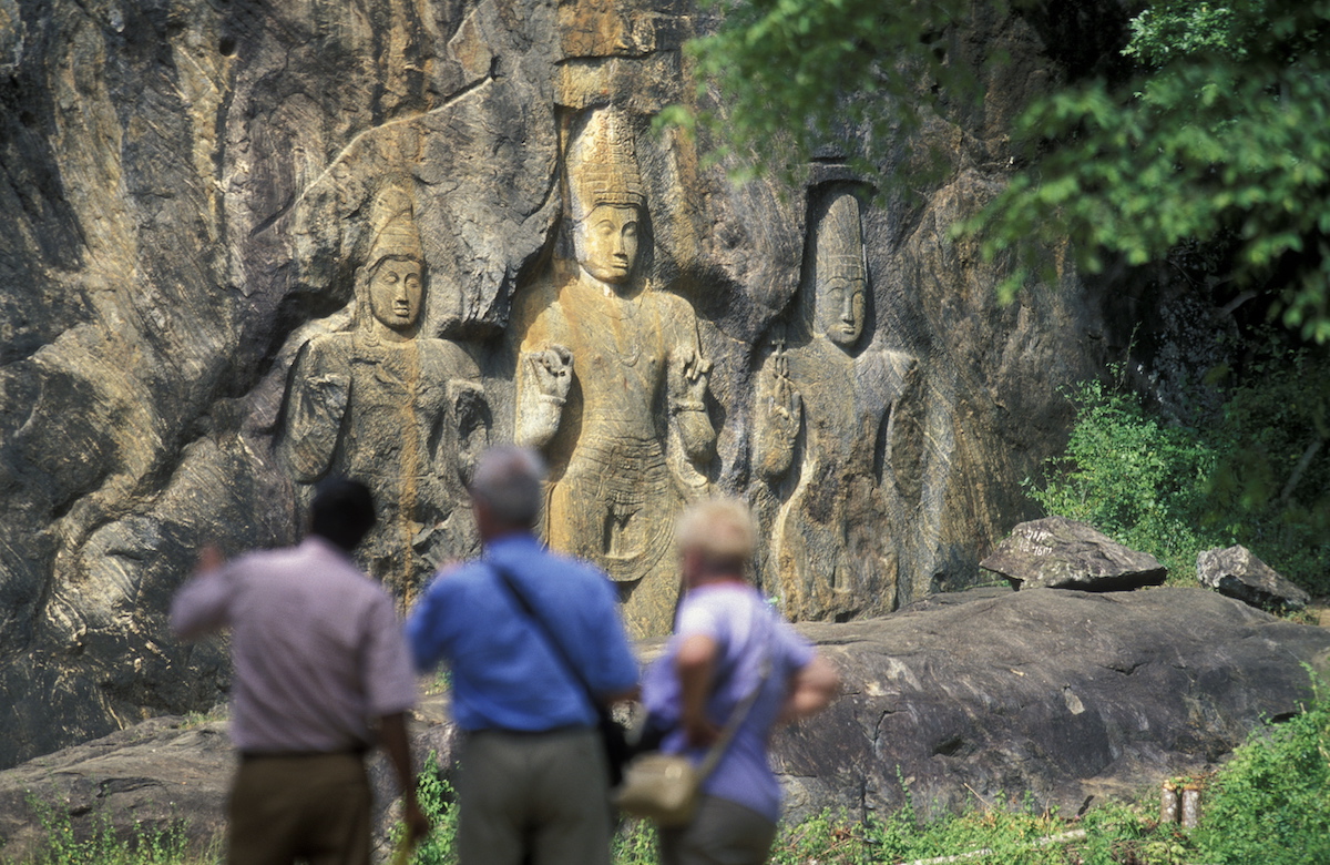Tourists look at large ancient carvings in Sri Lanka.
