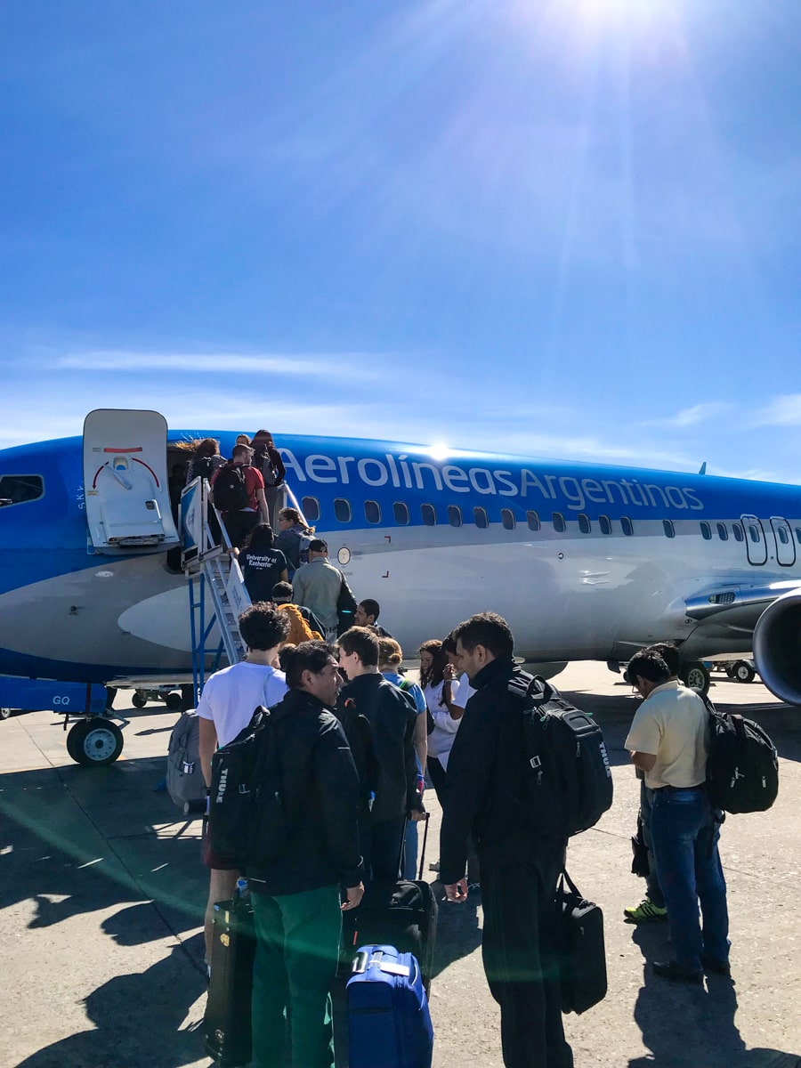People queue up to get on blue and white an Aerolineas Argentinas plane