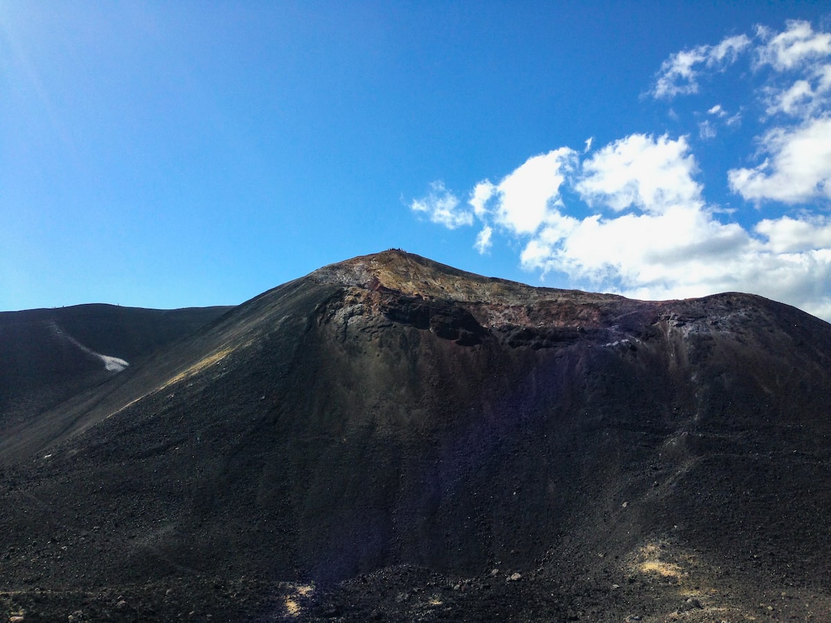 A mountain with black volcanic ash from recent activity on a clear blue sky day in Nicaragua. 