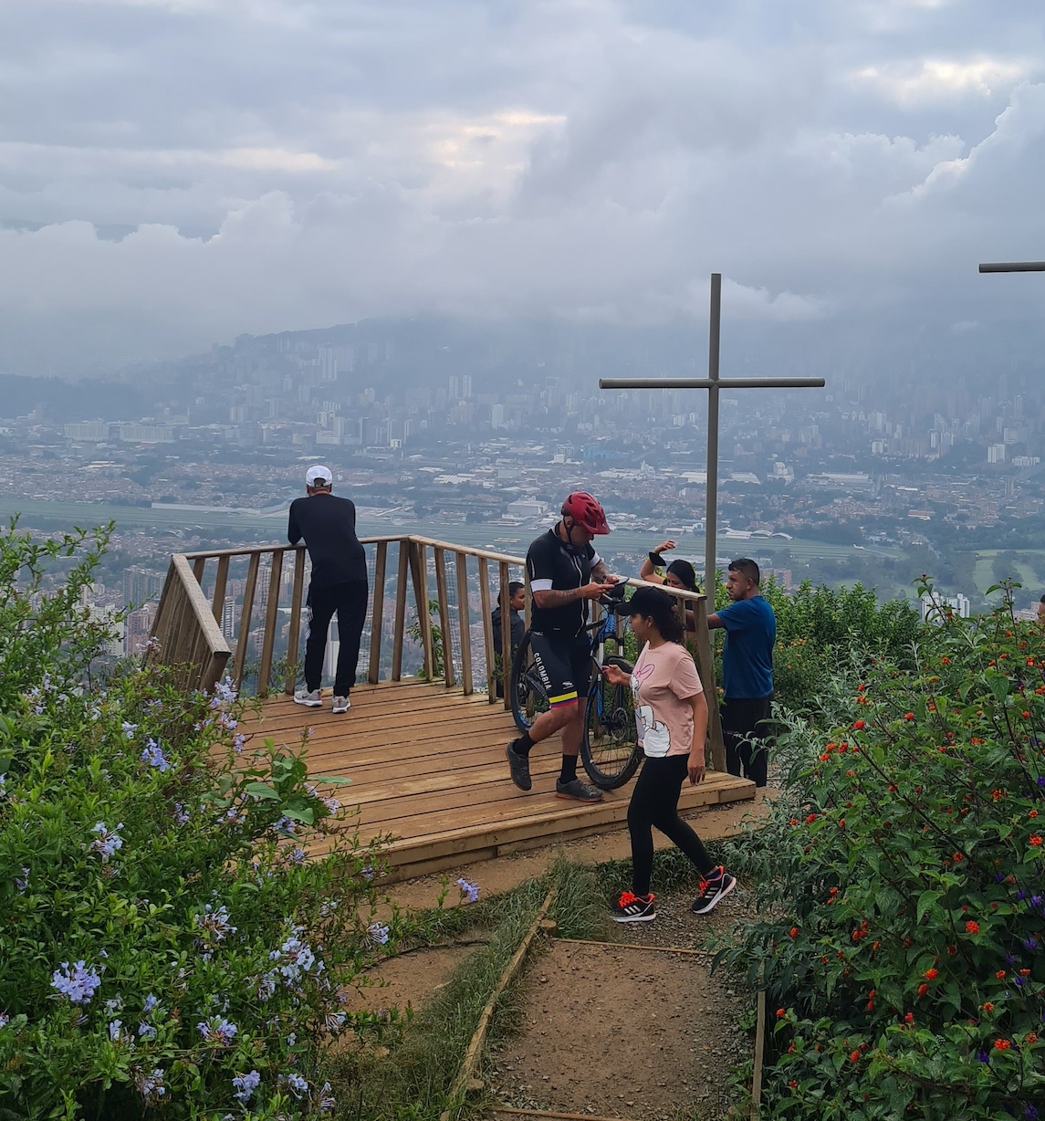 Hikers look out from a viewpoint on a misty day at the hill of three crosses in Medellin, Colombia 