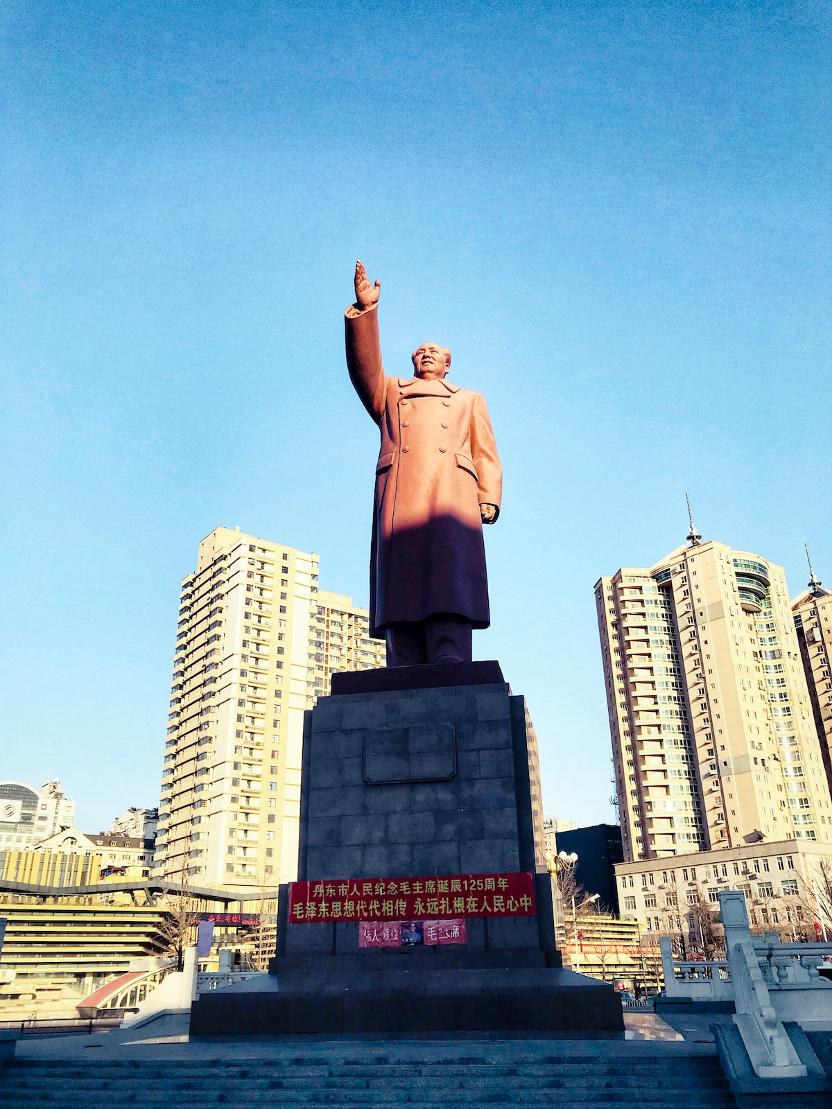 A giant bronze statue of Chairman Mao with his arm raised high in Dandong, China