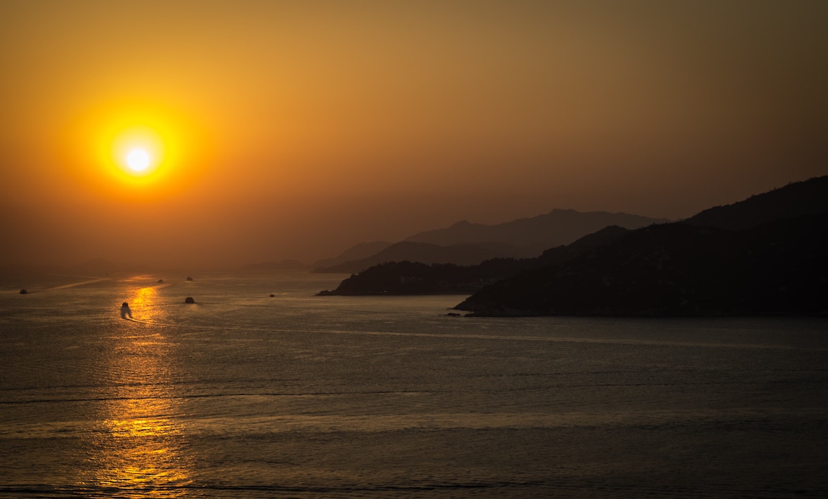 Boats riding on the sea at sunset near hilly mountains at Cheung Chau Island, Hong Kong