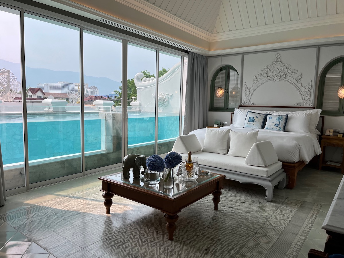 A hotel room with white bedding and a private pool overlooks large mountains in  Old Town, Chiang Mai