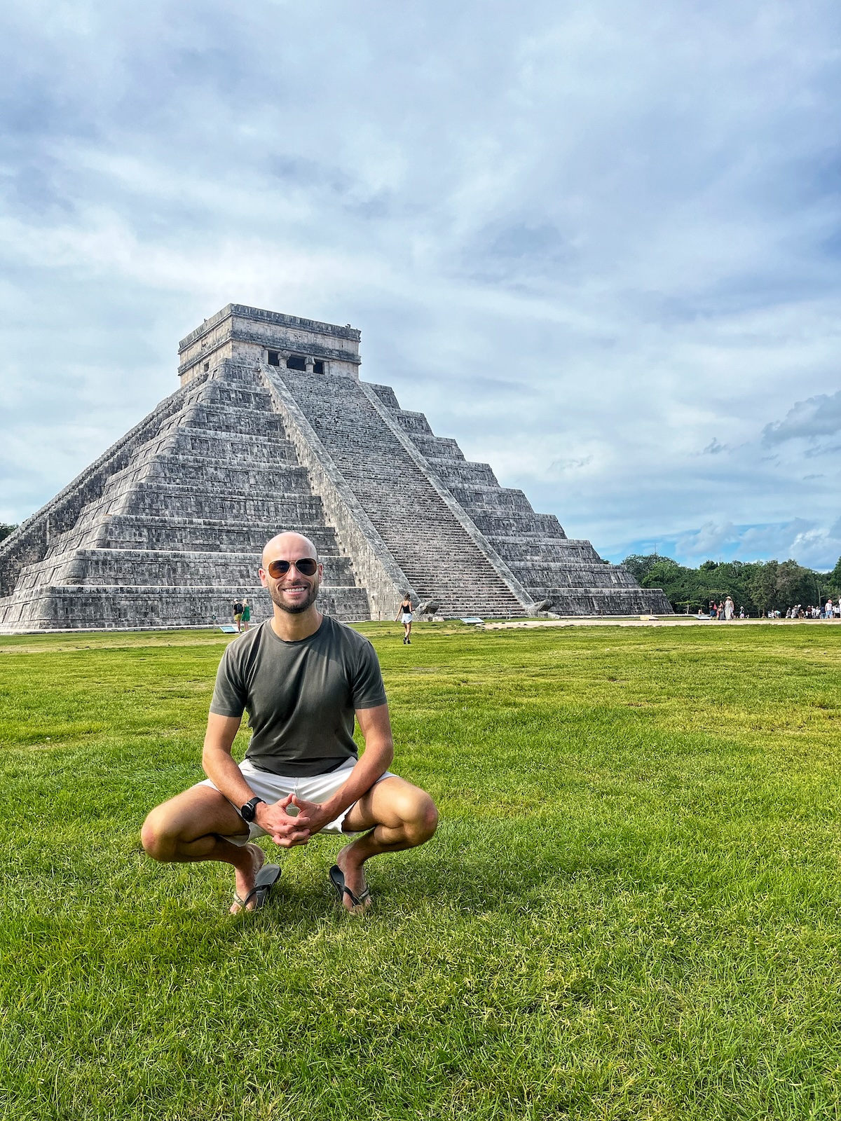 A tourist crouches down in front of Chichen Itza, one of the most famous landmarks in Mexico