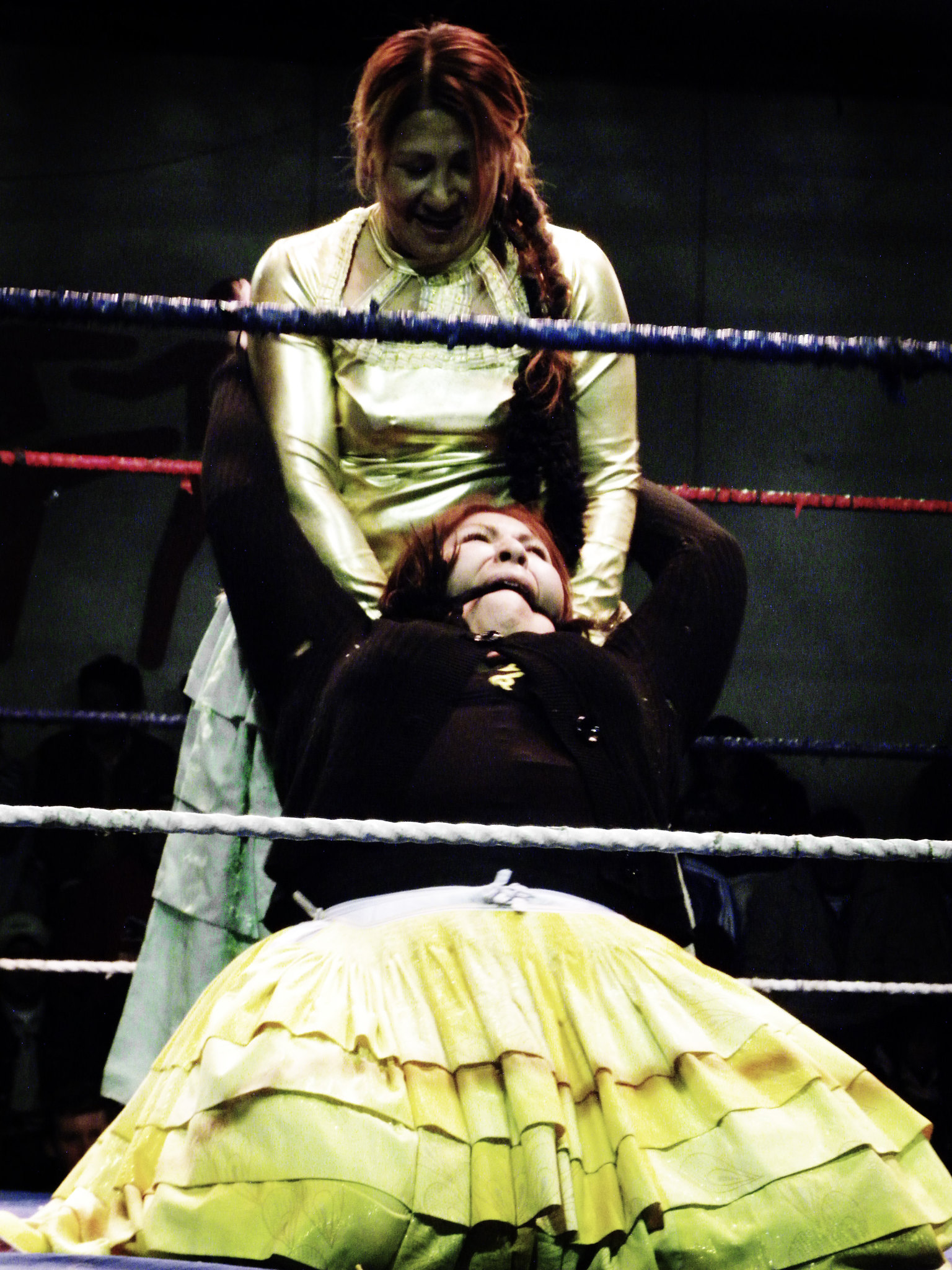 A female wrestler smiles as she holds another female fighter during a wrestling match in La Paz, Bolivia