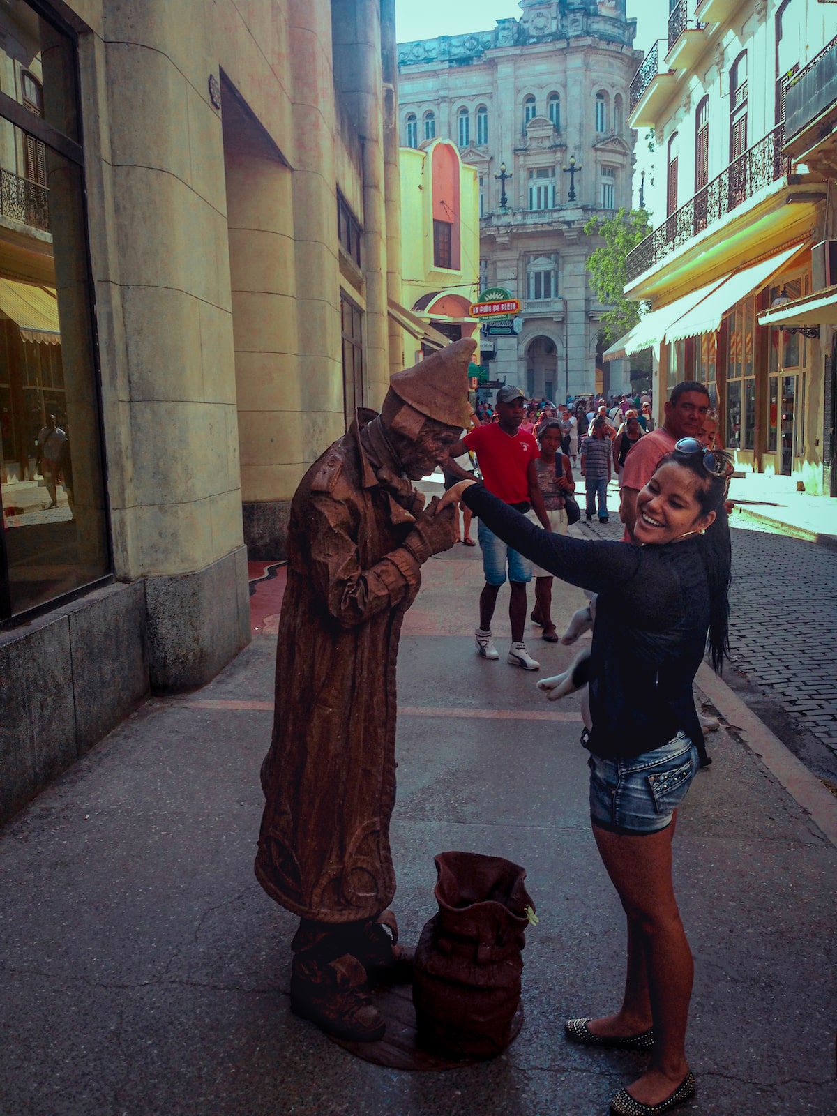 A street performer kisses a woman's hand as she laughs in Downtown Havana, Cuba.