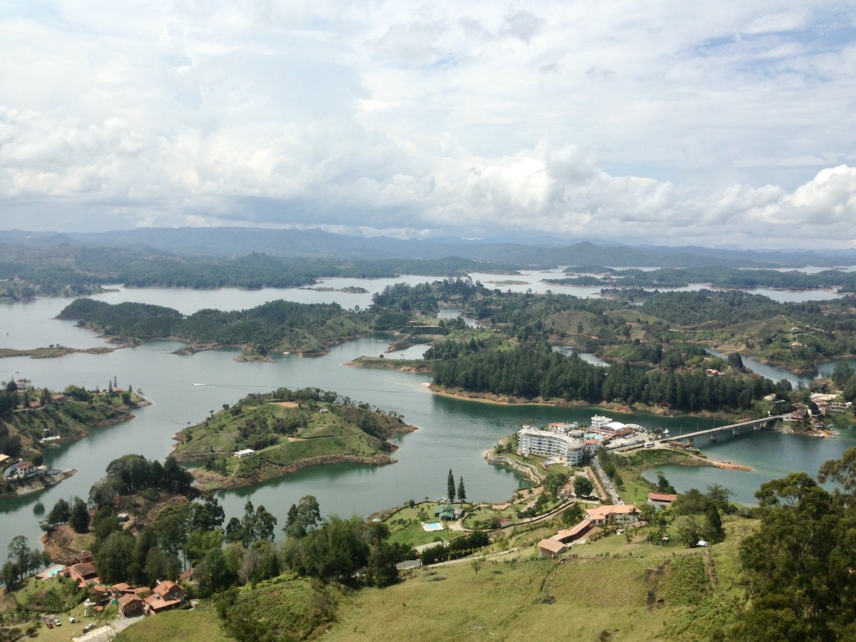 A stunning bird's eye landscape of small green islands surrounding a bridge over a body of water 