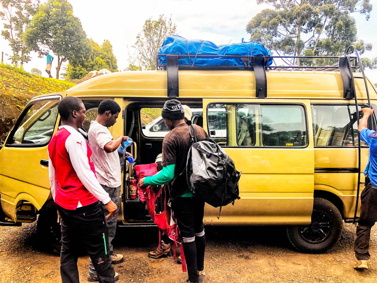 A team of climbers wait outside of a yellow van.