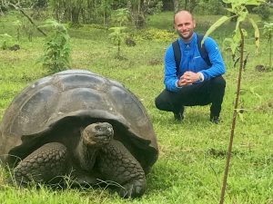 A man poses alongside a giant Galapagos Tortoise