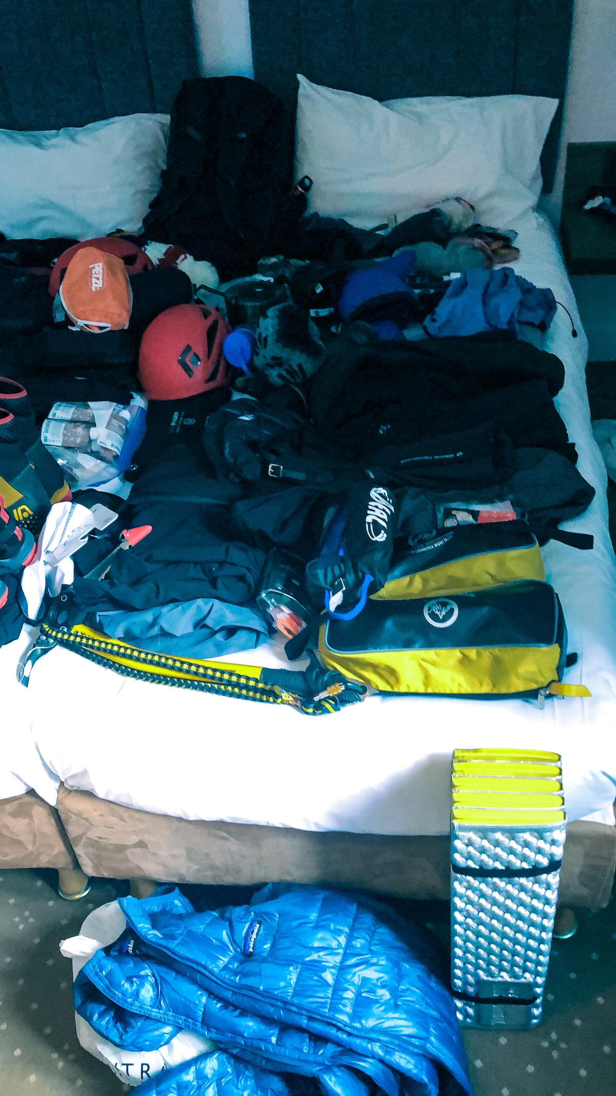 Mountain equipment is laid out on a hotel bed.