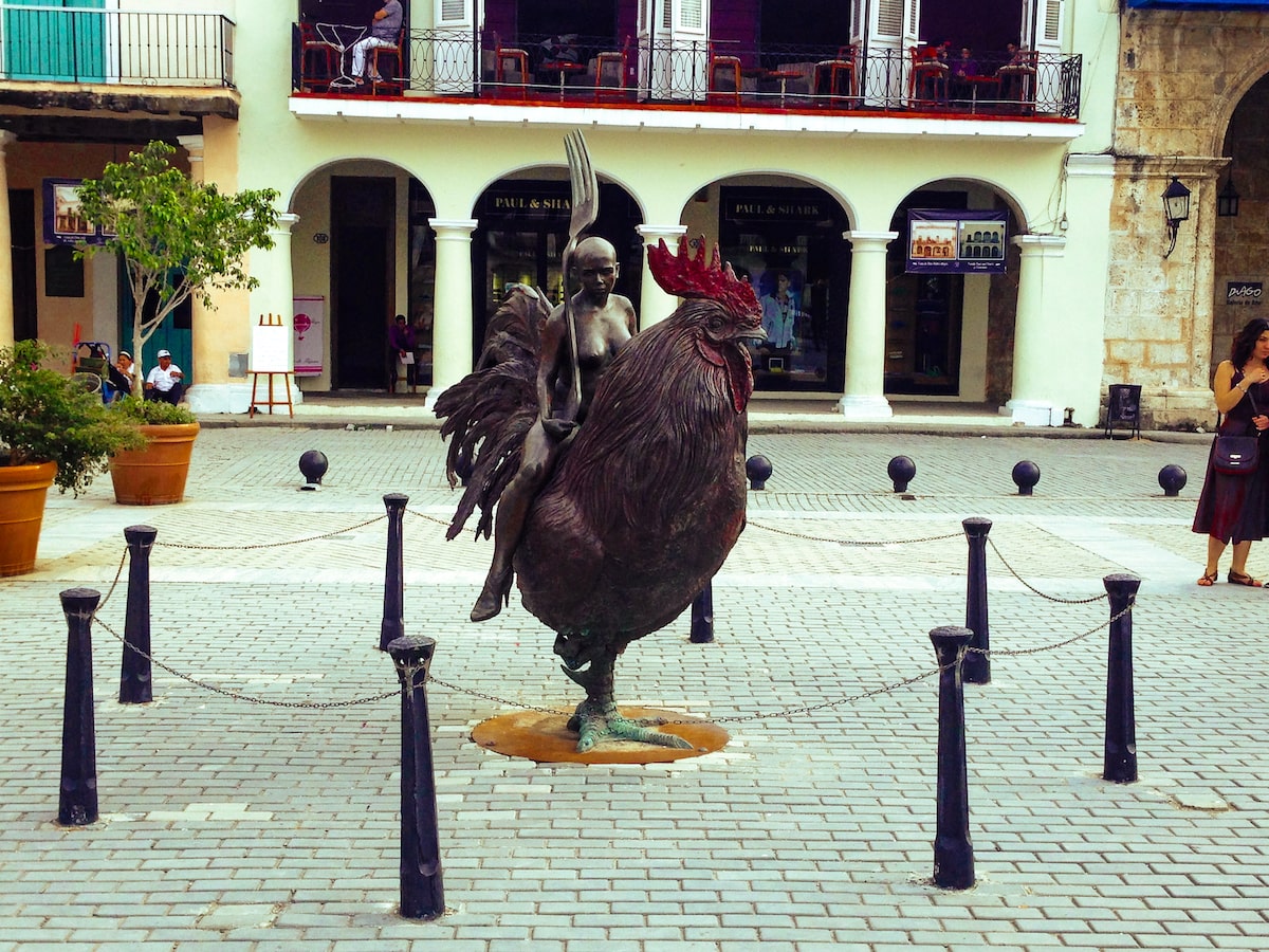 Woman with a large fork on a chicken statue in Old Town, Havana in Cuba.