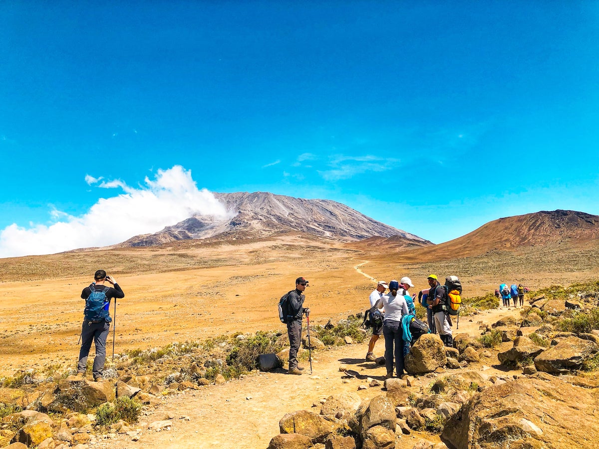 Climbers gather around a trail as they begin to climb Mount Kilimanjaro.