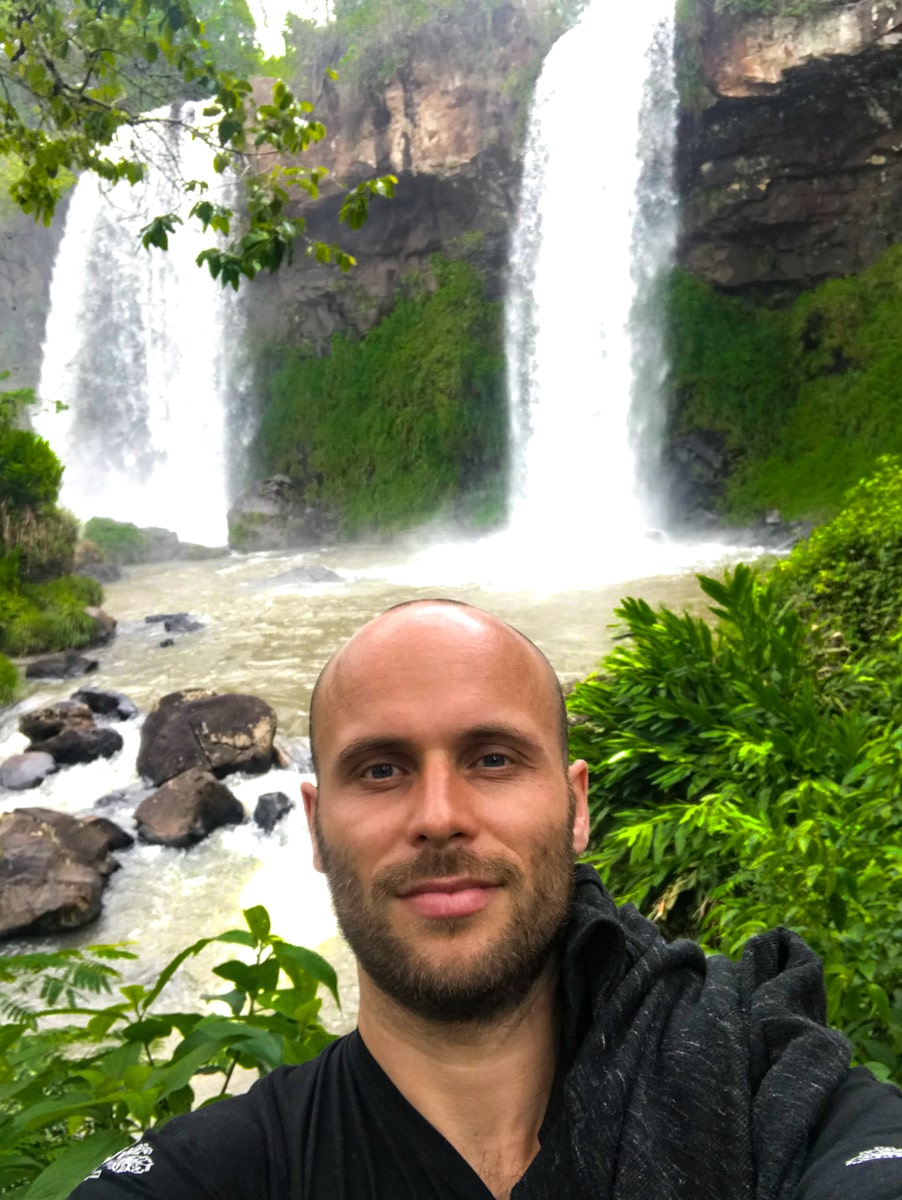 A man takes a selfie near two waterfalls 