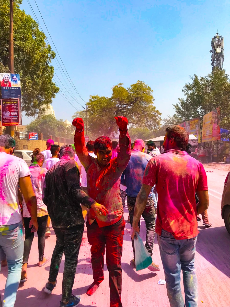A man throws powder during Holi in the street during the day