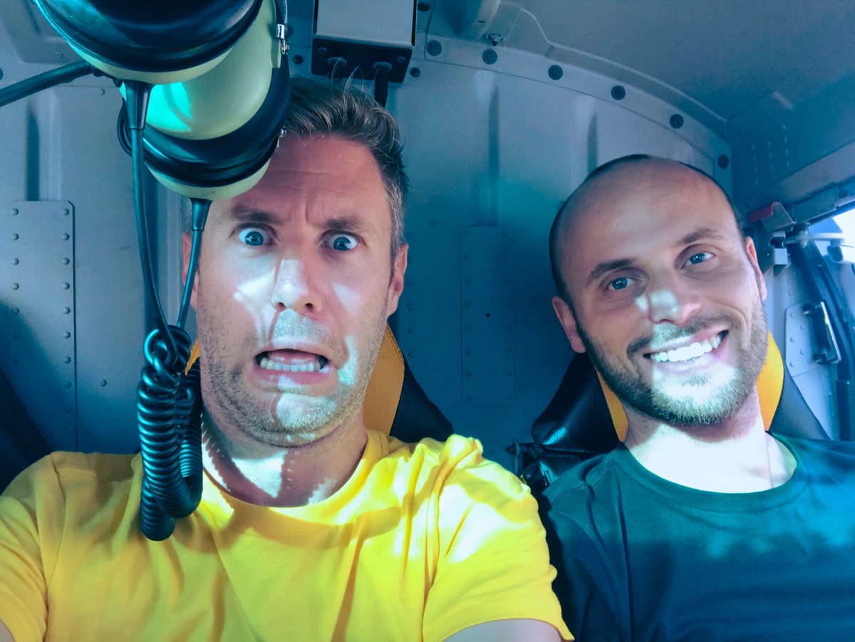 Two men pose inside a helicopter en route to climbing Puncak Jaya in West Papua, Indonesia