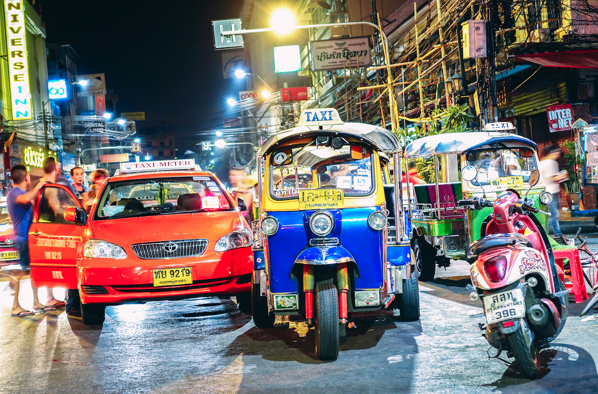 Road street life and traffic with tuk-tuk rickshaw taxis near Khao San Road Bangkok in Thailand 