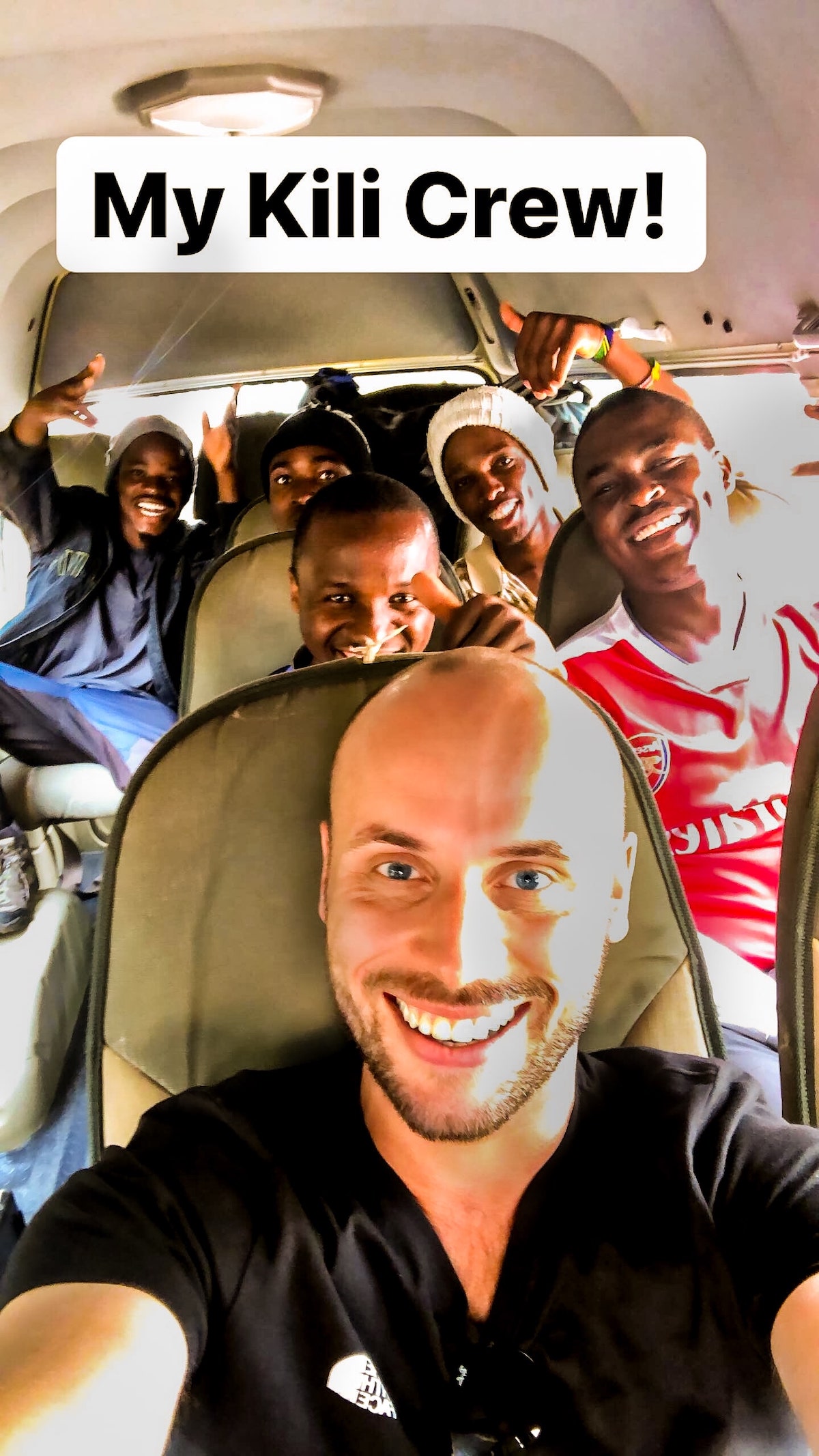 A group of men smile for a selfie photo inside a van.